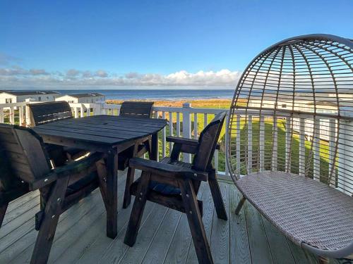 a wooden table and chairs and a bird cage on a deck at Millars Caravan in Ayr