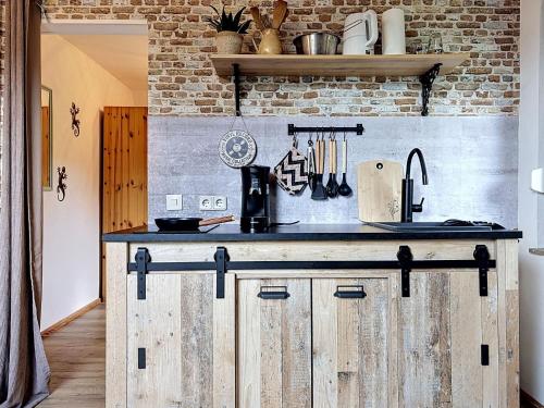 a kitchen with a counter with wooden cabinets and a brick wall at Apartment Eifelhome One nahe Nürburgring by Interhome in Fuchshofen