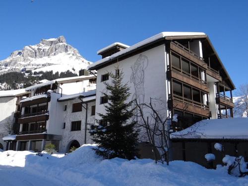 a building with a christmas tree in the snow at Apartment Am Dürrbach 4-413 by Interhome in Engelberg