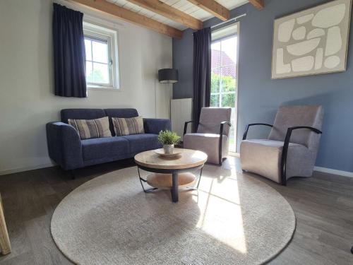 a living room with a couch and a table and chairs at Holiday Home Zeeuwse Cottage Wemeldinge-1 by Interhome in Wemeldinge