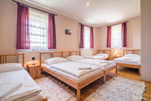 three beds in a room with red curtains at Panoráma Vendégház Bükkösd in Bükkösd