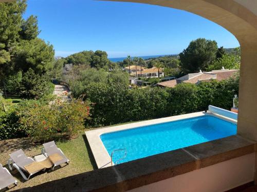 a swimming pool in a yard with two lawn chairs at Villa Villa Louise by Interhome in Jávea