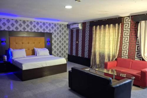 a bedroom with a bed and a couch and a bed and a chair at Paris Suites in Festac Town