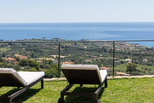 two chairs on a hill with the ocean in the background at Villa Eftychia - Panoramic Sea View in Svoronata