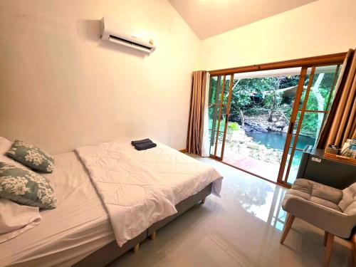 a bedroom with a bed and a window and a chair at ลิตเติ้ล แคมป์ ชะอม in Ban Bung Mai
