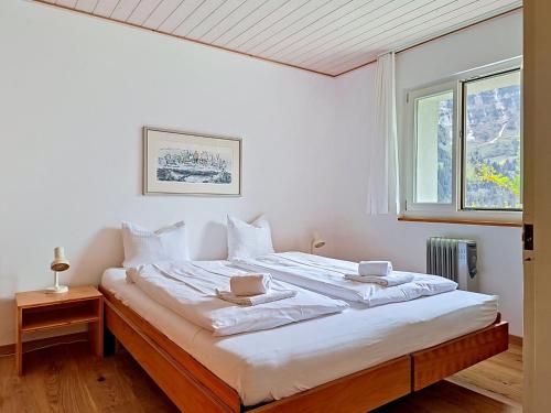 a bedroom with a large bed with white sheets and a window at Apartment Chalet Holzwurm-1 by Interhome in Grindelwald