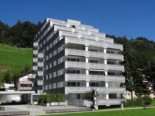 a tall white apartment building with a hill in the background at Apartment Sunnmatt 752 by Interhome in Engelberg