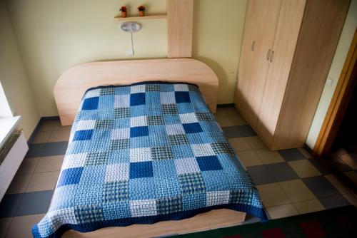 a bed with a blue and white checkered blanket at Eiva in Marijampolė