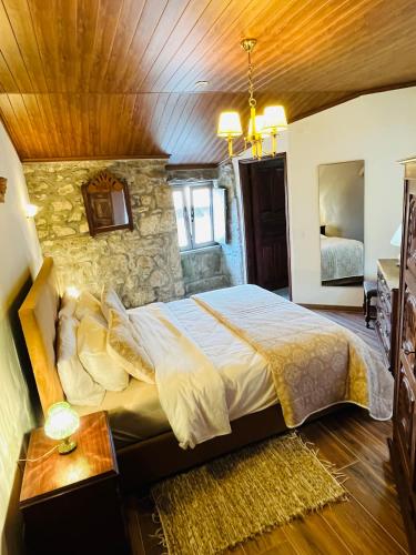 a bedroom with a large bed and a stone wall at Vila Adelaide in Campos