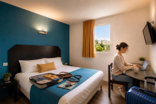 a woman sitting at a desk in a hotel room at Audotel in Carcassonne