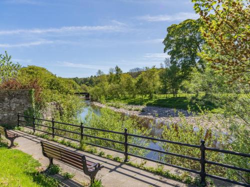 a bench sitting next to a fence next to a river at Riverside Cottage - Uk32405 in Stanhope