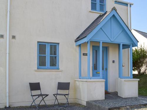 two chairs sitting outside of a house with a blue door at Goslings in Marloes