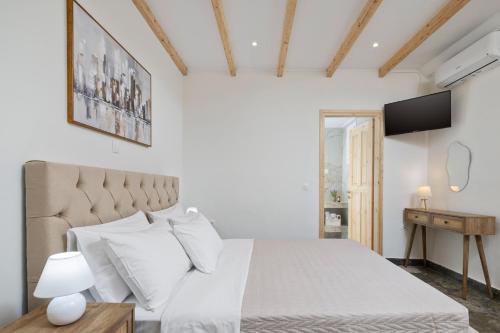 a white bedroom with a bed and a television at Pavlos & Sofia Harmony Villa with Private Pool in Corfu