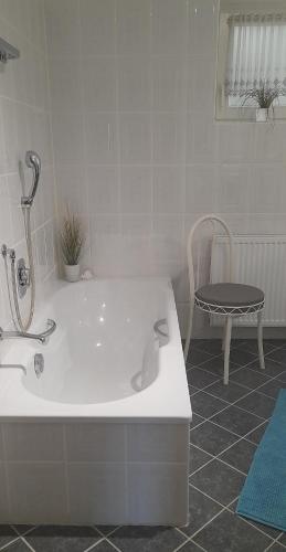 a bath tub in a bathroom with a chair at Ferienwohnung Gartentraum in Oberzent