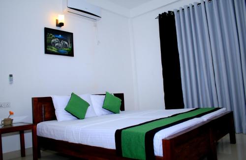 een slaapkamer met een bed met groene en witte kussens bij Seasons Villa in Dambulla