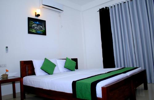 a bedroom with a bed with green and white pillows at Seasons Villa in Dambulla