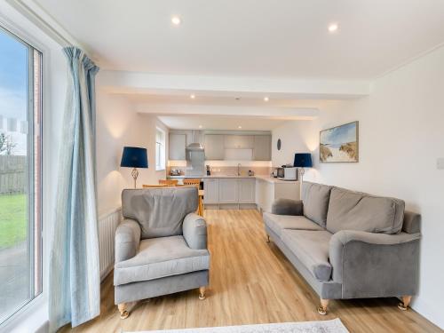 a living room with two chairs and a kitchen at Cartmel Cottage in Lindale