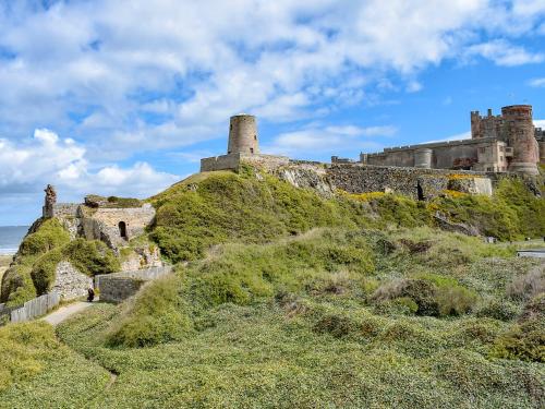 an old castle on top of a grassy hill at The Caddy's Lodge - Uk47762 in Bamburgh