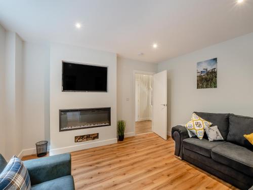 a living room with a couch and a flat screen tv at The Caddy's Lodge - Uk47762 in Bamburgh