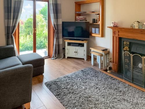 a living room with a tv and a fireplace at The Cottage in Whiting Bay