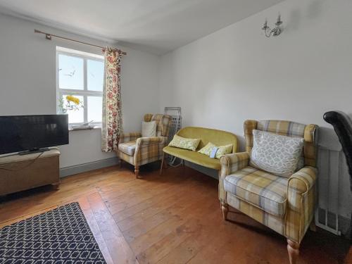 a living room with two chairs and a flat screen tv at Fronisaf - Uk49775 in Llanfair Talhaiarn