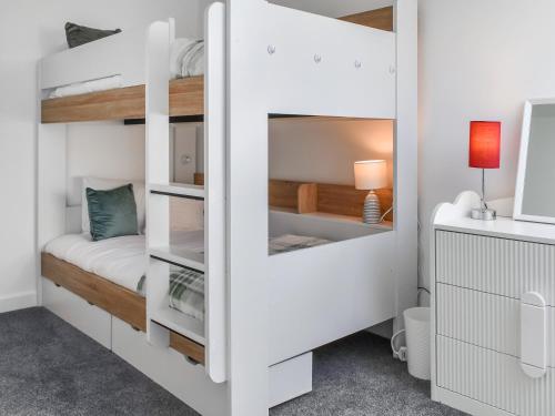 a white bunk bed in a room with a desk at Strandside Townhouse in Bude