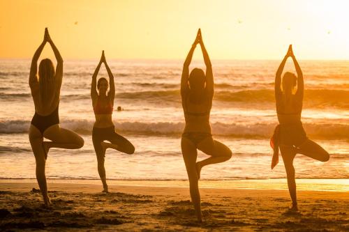 a group of four women doing yoga on the beach at Selina Santa Teresa North in Santa Teresa Beach