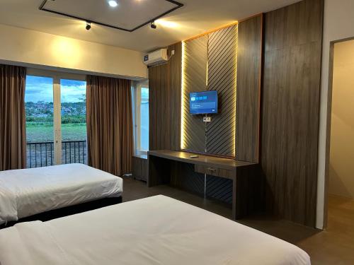 a hotel room with two beds and a television at Bwalk Hotel & Villa Malang in Sengkaling