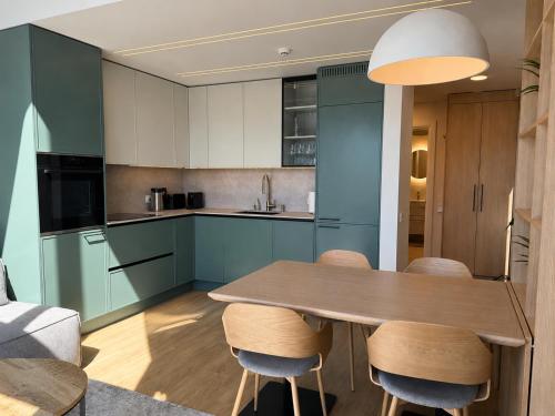 a kitchen with a wooden table and some blue cabinets at Pirtelių resort - Mėlynasis namelis in Kiauleikiai