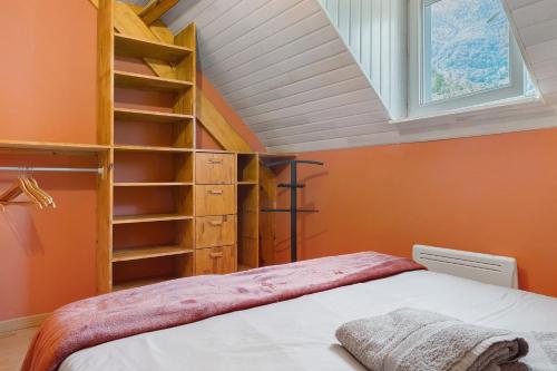 a bedroom with a ladder and a bed with an orange wall at L'Appartement des Trois Vallées in Villelongue