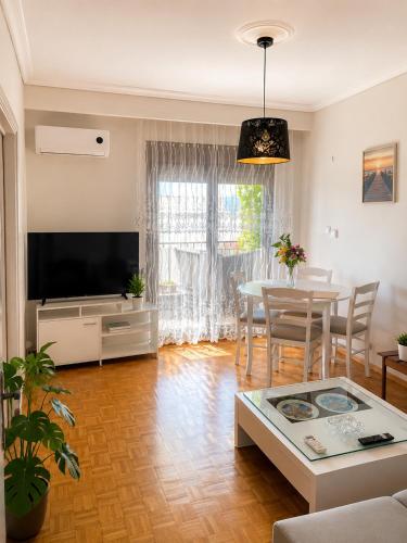 a living room with a television and a table at Nickolas Sea View Apartment in Paleo Tsifliki
