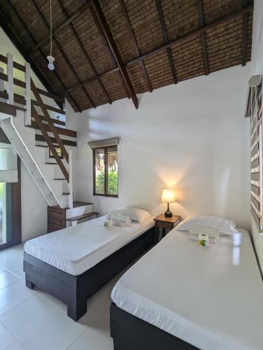 a bedroom with two beds and a staircase at Villa Peray Siargao in General Luna