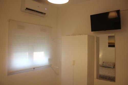 a white room with a window and a television on the wall at TangoSierraResidences in Alcochete