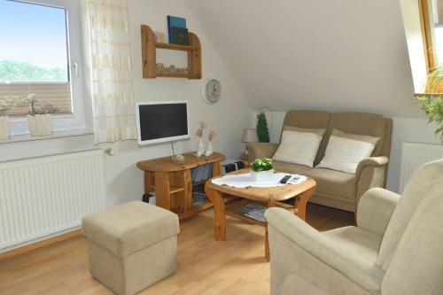 a living room with a couch and a tv at Ferienwohnung Sonnenberg, 25502 in Weener