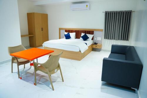 a bedroom with a bed and a table and a chair at Shalini Residency in Nalgonda