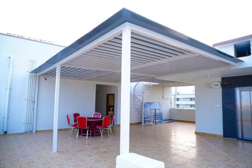 a patio with red chairs and a table under awning at Shalini Residency in Nalgonda