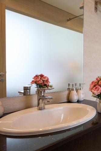 a sink in a bathroom with flowers in a mirror at Viona Beach Hotel - Marina Phu Quoc in Phú Quốc