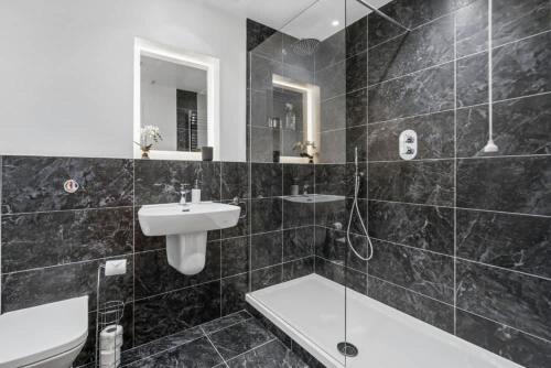 a black and white bathroom with a sink and a shower at Windsor Castle Views - Spacious Flat - By Tempstay in Windsor