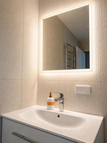 a bathroom with a white sink and a mirror at Pirtelių resort - Pilkasis namelis in Kiauleikiai