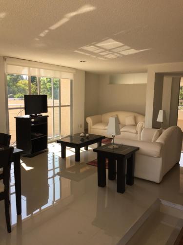 a living room with a couch and tables and a tv at Bosque de Magnolias 93 in Mexico City