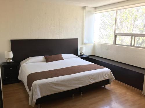 a bedroom with a large bed with a large window at Bosque de Magnolias 93 in Mexico City