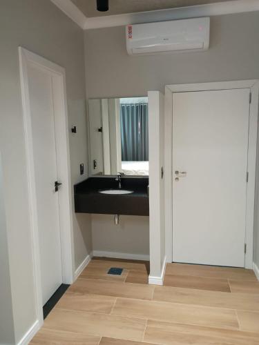 a bathroom with a sink and a mirror and a door at Hotel Premier in Santa Rita