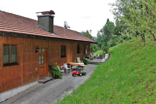 ein kleines Haus mit einem roten Traktor daneben in der Unterkunft Bocksleitnerhof in Wackersberg