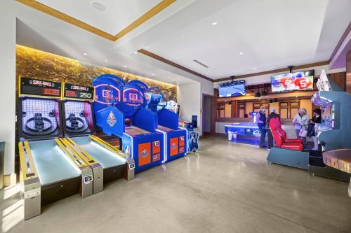 a game room with two arcade machines and people playing at GA181: 181 Glen Abbey in Kiawah Island