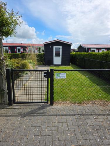 a gate in front of a house with a train at Chalet Olm Ferienpark Olmenduin Zeeland 4 Pers familienfreundlich Hunde willkommen in Serooskerke