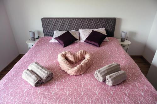 a bed with a pink bedspread with two pillows and a heart shaped at Kuća za odmor Serdar in Slavonski Brod