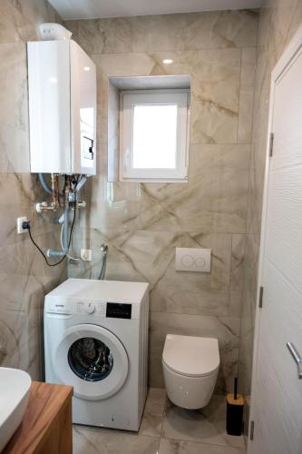 a bathroom with a washing machine and a toilet at Kuća za odmor Serdar in Slavonski Brod