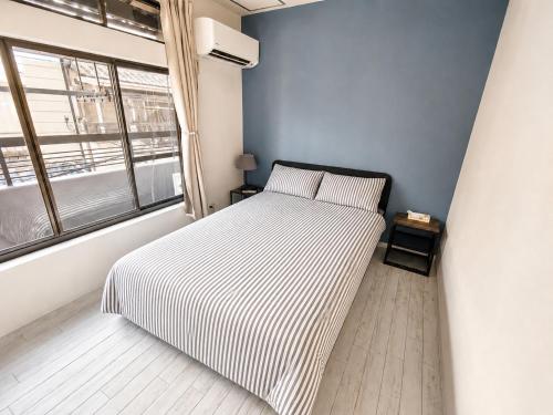 a bedroom with a bed with striped sheets and a window at New Entire Family House 1 Min to Metro Umeda Direct in Osaka