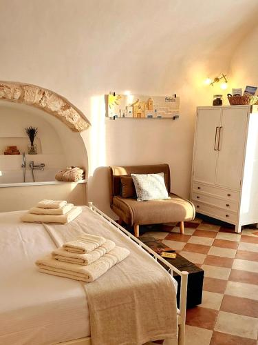 a bedroom with a bed and a chair and a refrigerator at La Suite di Alizeh in Ostuni