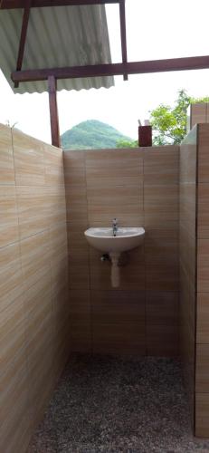 a bathroom with a sink in a wooden wall at Bilva Garden Penida in Polilit